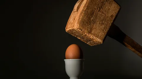 A photo of a wooden mallet about to smash an egg. Illustrates [alt text].