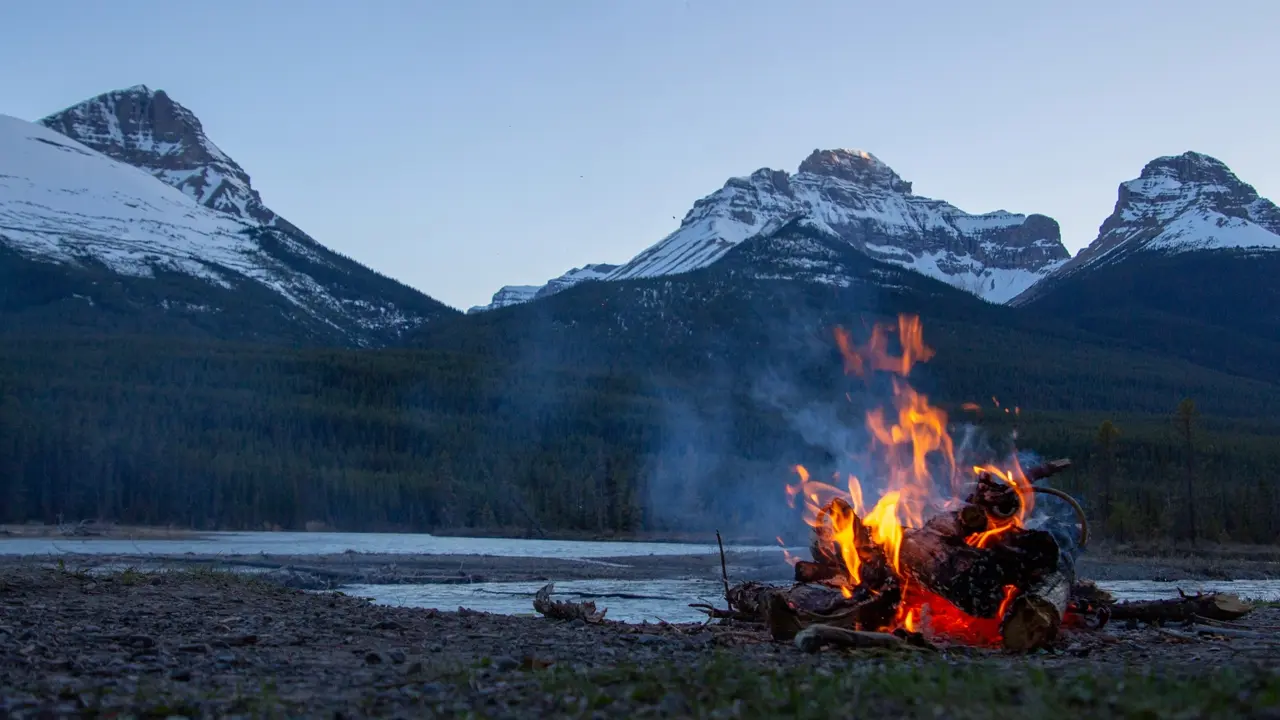 A photo of a campfire in a beautiful mountanous region. Illustrating Lyre RPG Music's album creation.