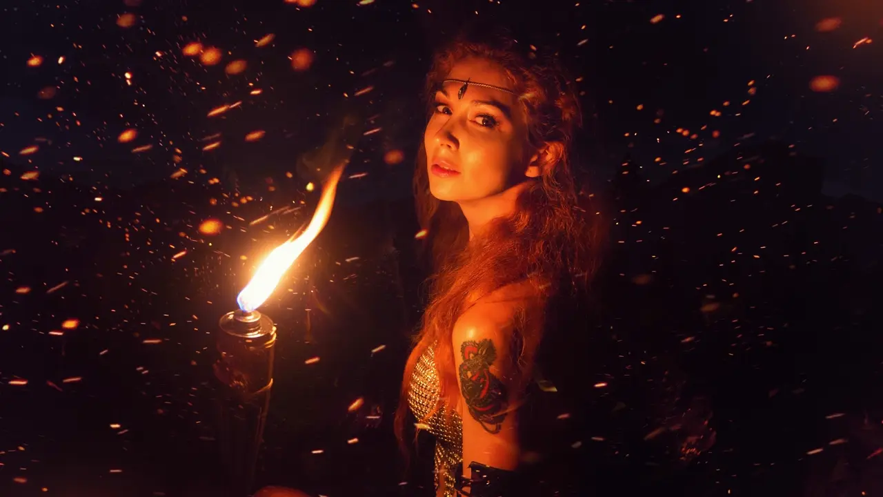 A photo of a fantasy-dressed woman holding a torch. Illustrates [alt text].