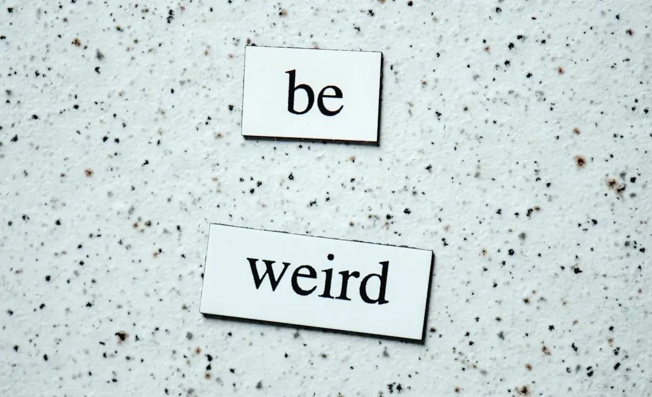 A photo of two pieces of cardboard written "be" and "weird."-