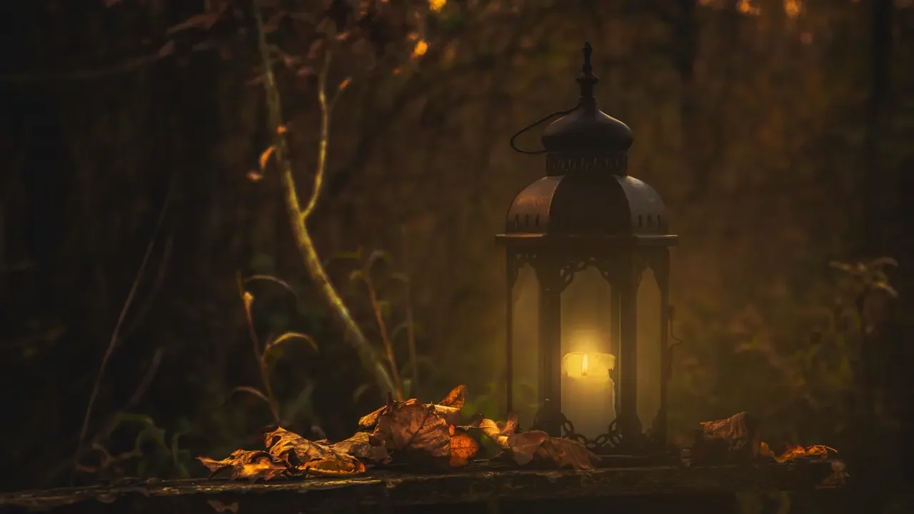 yellow-pillar-candle-in-black-lantern Photo of a yellow pillar candle in black lantern giving the forest light.