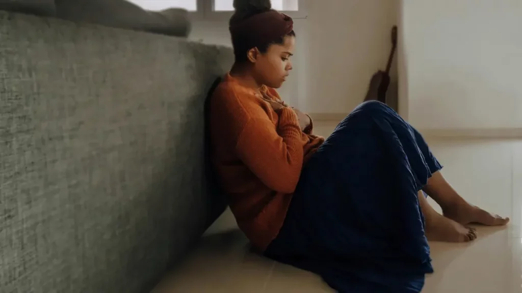 woman-in-orange-long-sleeve-shirt-sitting-on-gray-couch Woman in orange long sleeve shirt sitting on gray couch. Themes of social anxiety.