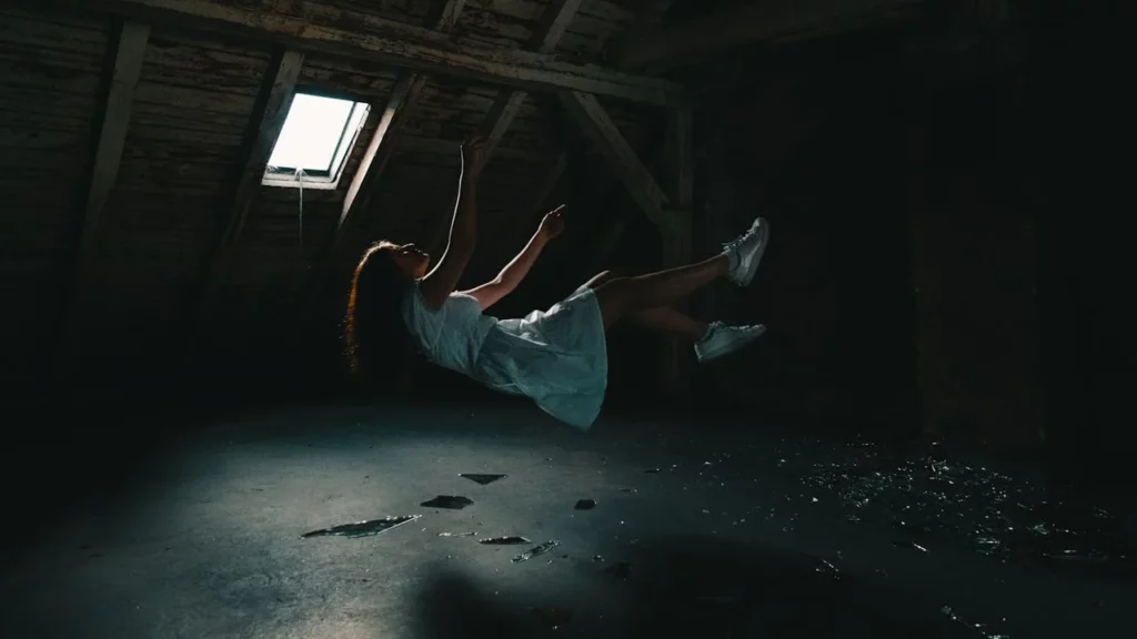 A photo of a woman falling to the floor from the ceiling of a loft or attic