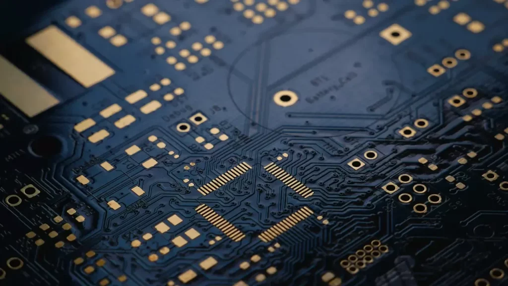 A low exposure photograph of an unsoldered Printed Circuit Board (PCB) with ENIG (Gold) finish. Themes of glossary.