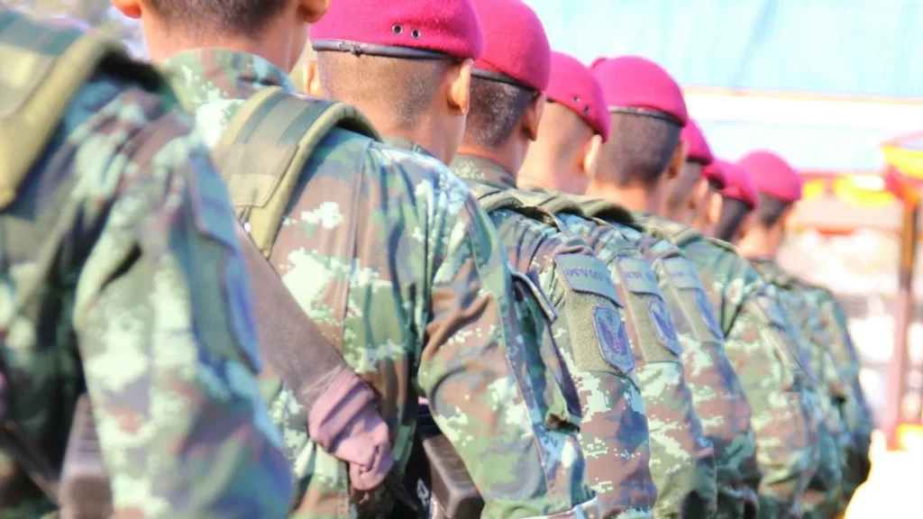 A photo of a regiment of soldiers standing in line for inspection wearing combat fatigues and red berets.