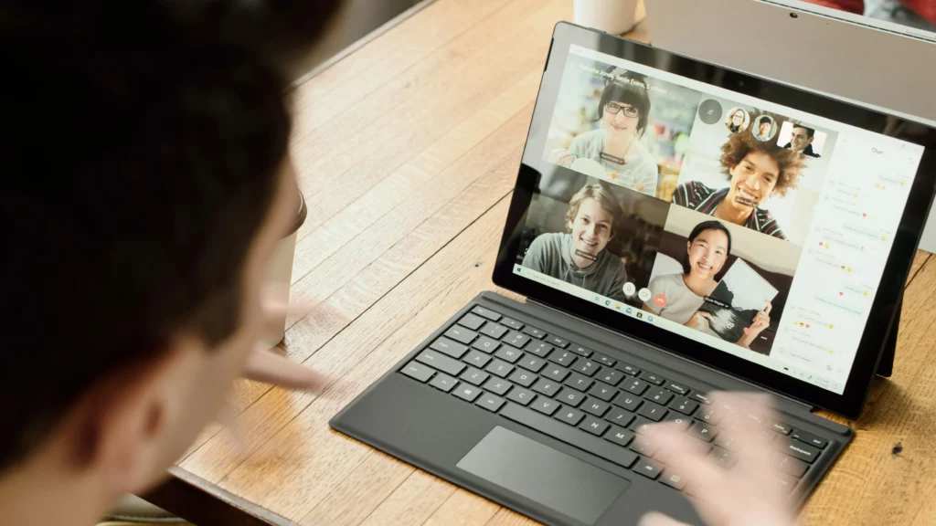 Person in blue long sleeve shirt using a computer for a video call.